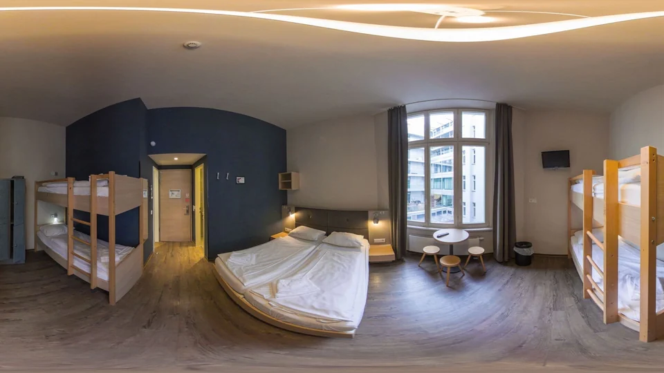 360°-Panorama eines hellen Zimmers mit Doppelbett, Etagenbetten und großem Sprossenfenster – Vorschaubild der virtuellen Tour